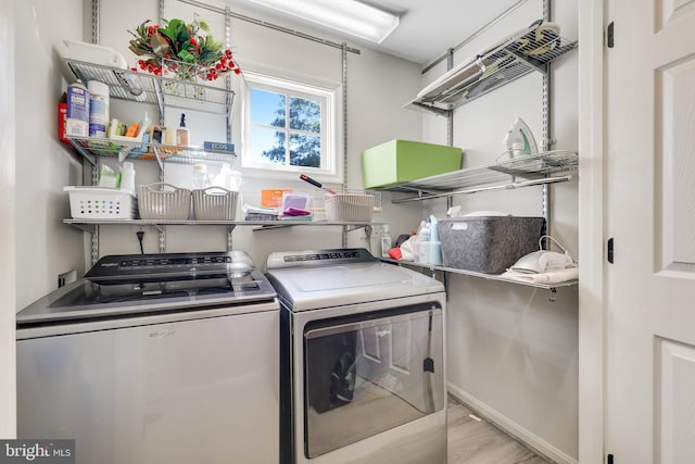 clothes washing area featuring light hardwood / wood-style flooring and washer and dryer