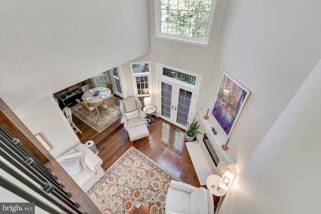 living room featuring french doors, a towering ceiling, and hardwood / wood-style floors