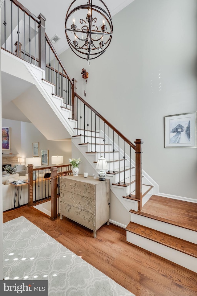 staircase featuring a notable chandelier, hardwood / wood-style flooring, and a high ceiling