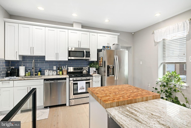 kitchen featuring sink, wooden counters, stainless steel appliances, light hardwood / wood-style floors, and white cabinets