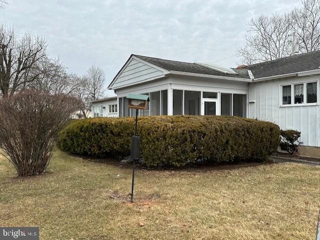 view of side of property with a yard and a sunroom