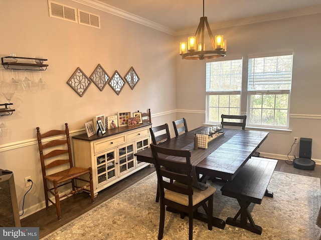 dining room featuring dark wood-type flooring, crown molding, and an inviting chandelier