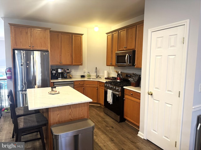 kitchen featuring a kitchen bar, sink, dark hardwood / wood-style floors, a kitchen island, and stainless steel appliances