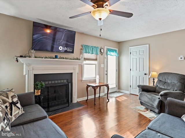 living room with hardwood / wood-style flooring, ceiling fan, and a textured ceiling