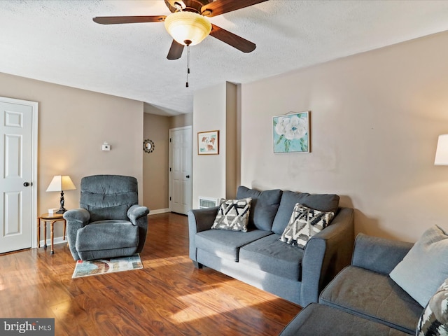 living room with ceiling fan, hardwood / wood-style flooring, and a textured ceiling