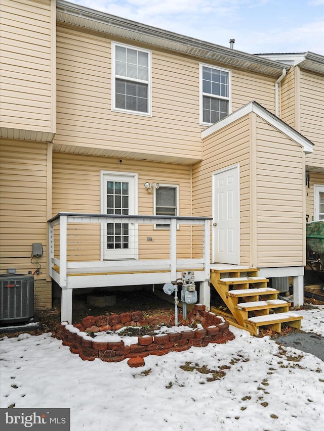 snow covered back of property featuring central AC unit