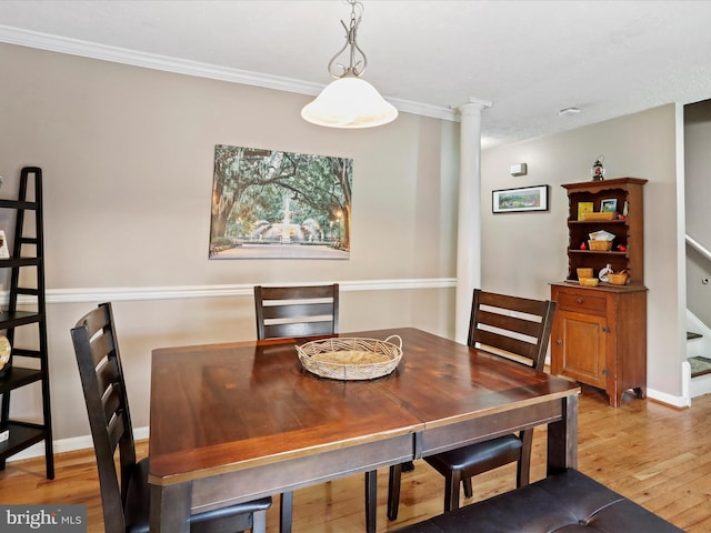 dining room featuring crown molding, ornate columns, and light wood-type flooring