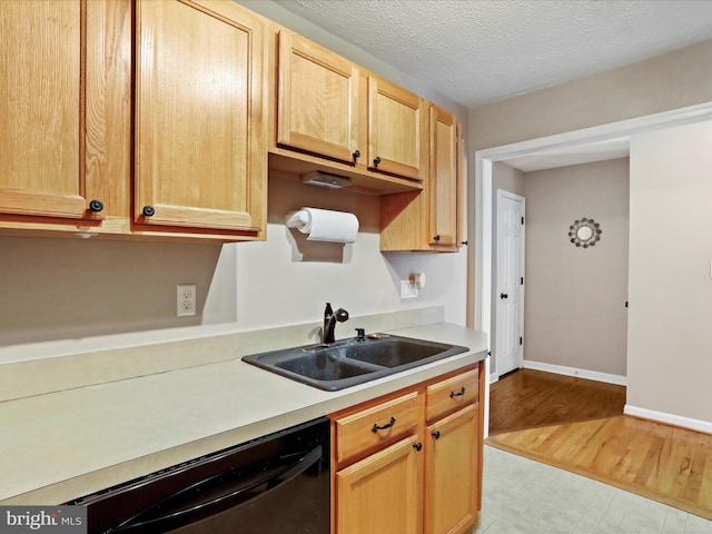 kitchen featuring sink, black dishwasher, a textured ceiling, light brown cabinetry, and light wood-type flooring