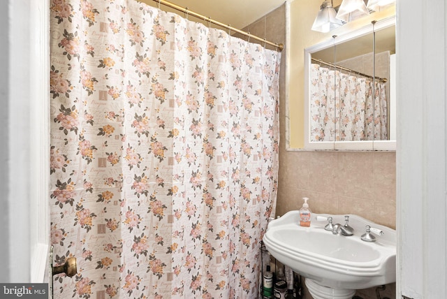 bathroom featuring a shower with curtain, sink, and tile walls