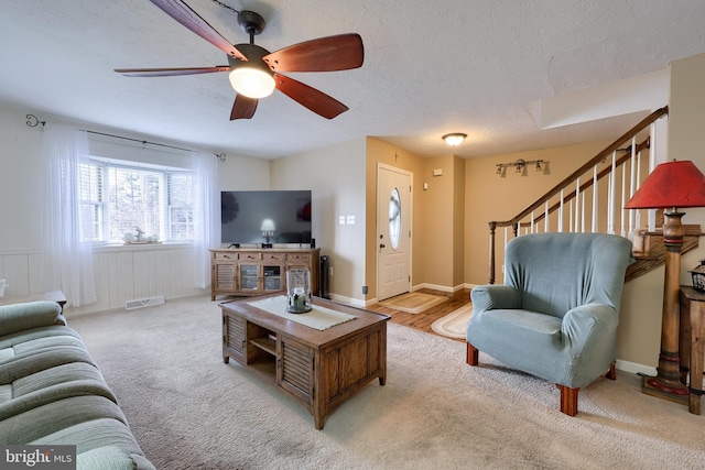 living room featuring ceiling fan, light colored carpet, and a textured ceiling