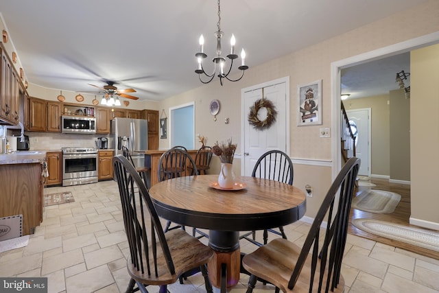 dining area featuring sink and ceiling fan with notable chandelier