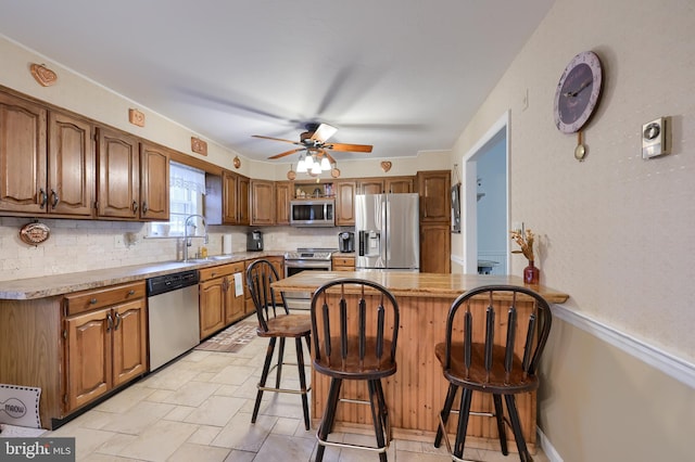 kitchen featuring sink, backsplash, stainless steel appliances, a center island, and a kitchen bar