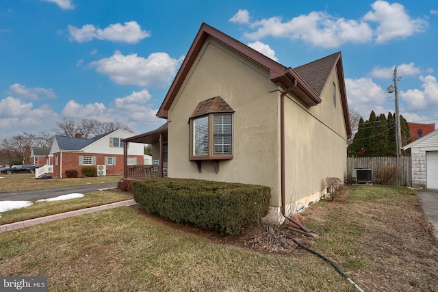 view of side of property featuring cooling unit, a garage, a yard, and a porch