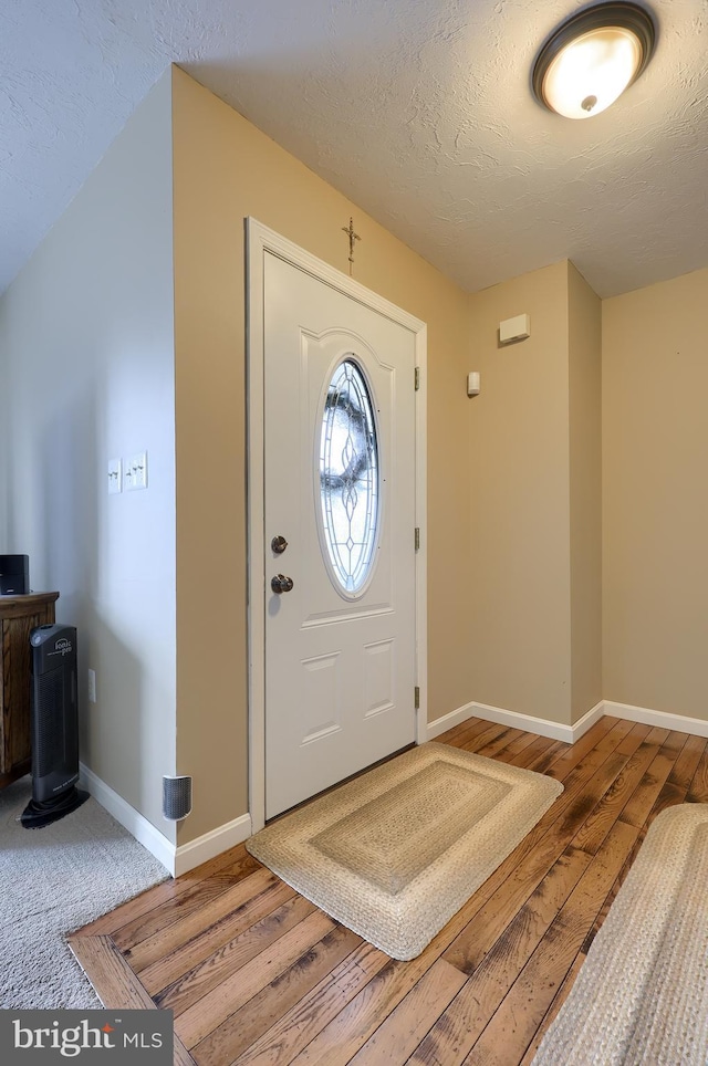 foyer entrance with hardwood / wood-style floors and a textured ceiling