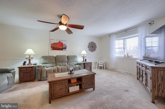 carpeted living room featuring ceiling fan and a textured ceiling