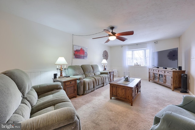 living room featuring ceiling fan, light carpet, and a textured ceiling