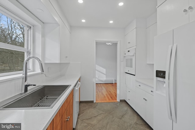 kitchen featuring sink, white cabinets, and white appliances