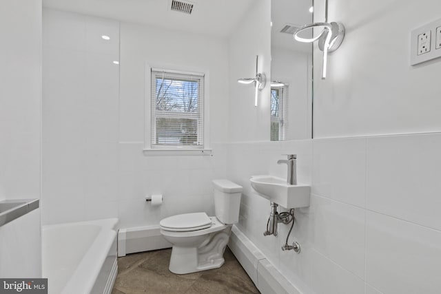 bathroom featuring tile walls, a bath, and toilet