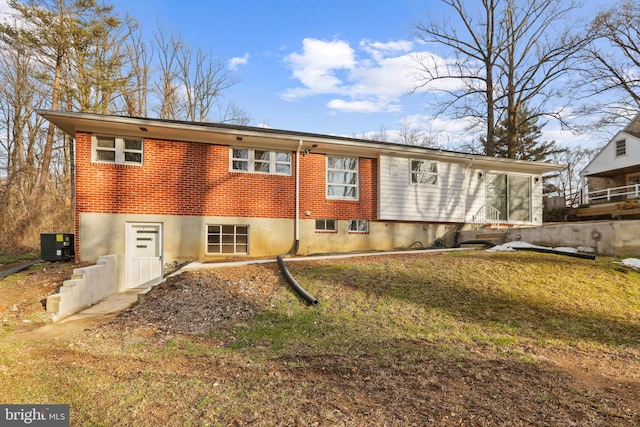 back of house with central AC unit and a yard