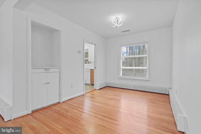 spare room with a baseboard radiator and light hardwood / wood-style flooring