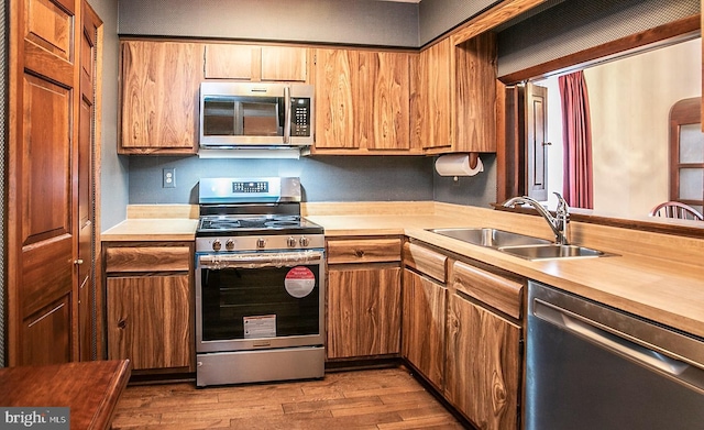 kitchen with sink, stainless steel appliances, and light wood-type flooring