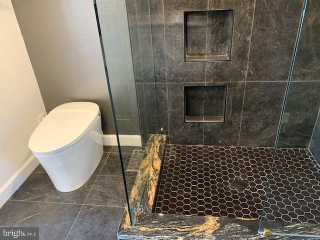 bathroom with a tile shower and toilet