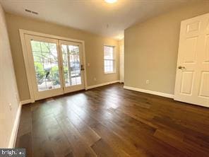 spare room featuring dark wood-style flooring, visible vents, and baseboards