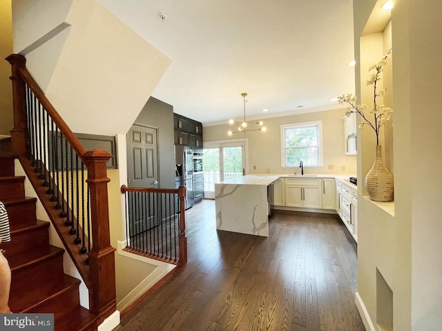 kitchen featuring white cabinetry, hanging light fixtures, a center island, light stone counters, and dark hardwood / wood-style flooring