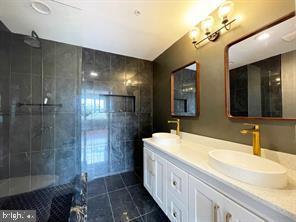 bathroom with vanity, a tile shower, and tile patterned floors