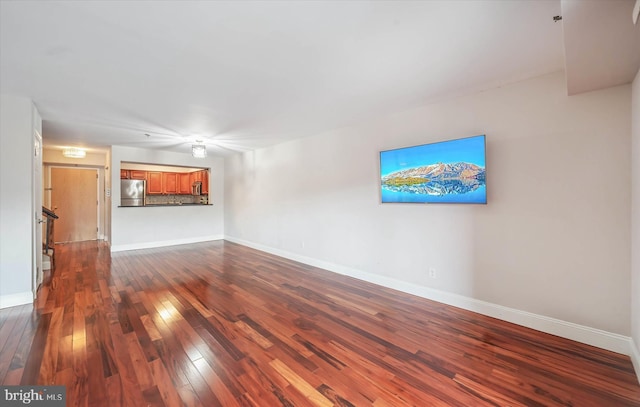 unfurnished living room with baseboards and dark wood finished floors