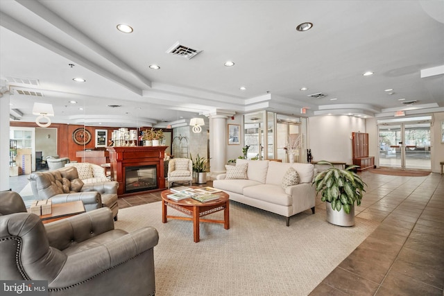 tiled living room with a tray ceiling and decorative columns