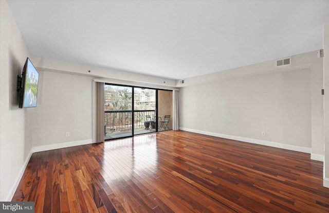 spare room with baseboards, visible vents, and wood finished floors