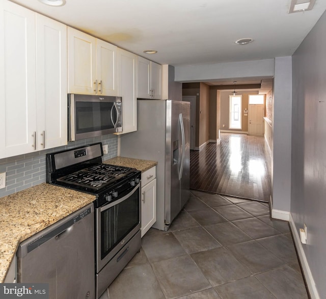 kitchen with light stone counters, decorative backsplash, stainless steel appliances, and white cabinets