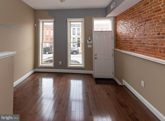 entrance foyer with dark hardwood / wood-style floors and brick wall