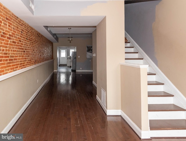 hallway featuring brick wall and dark hardwood / wood-style flooring