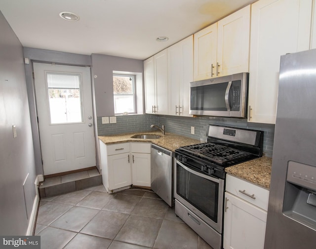 kitchen featuring white cabinetry, appliances with stainless steel finishes, light stone counters, and decorative backsplash