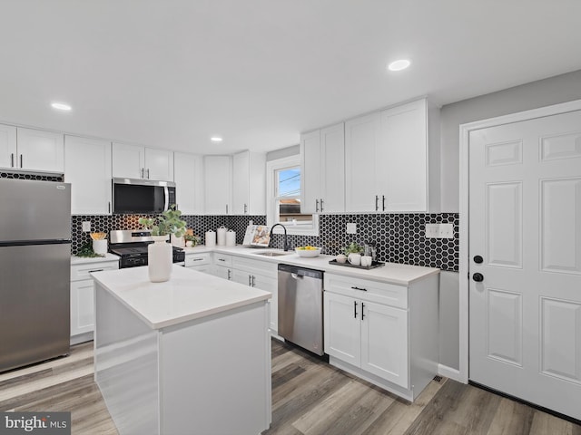 kitchen with appliances with stainless steel finishes, a center island, decorative backsplash, and white cabinets