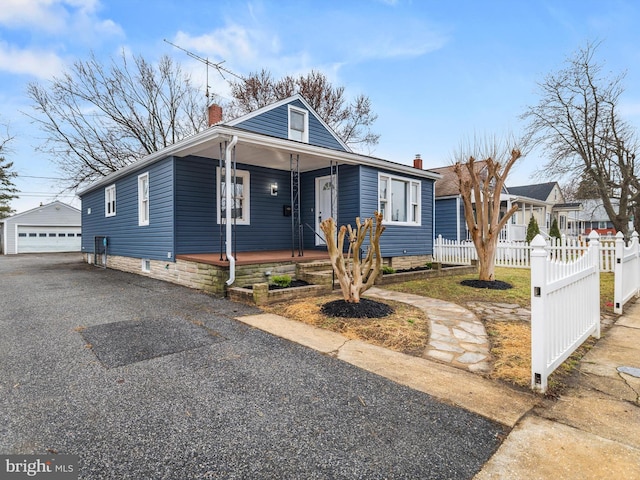 bungalow-style home with a garage, an outbuilding, and covered porch