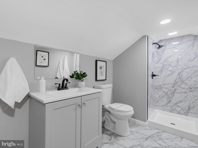 bathroom with a tile shower, vanity, vaulted ceiling, and toilet