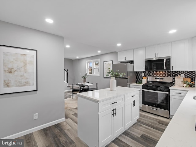 kitchen featuring white cabinetry, hardwood / wood-style flooring, tasteful backsplash, and appliances with stainless steel finishes