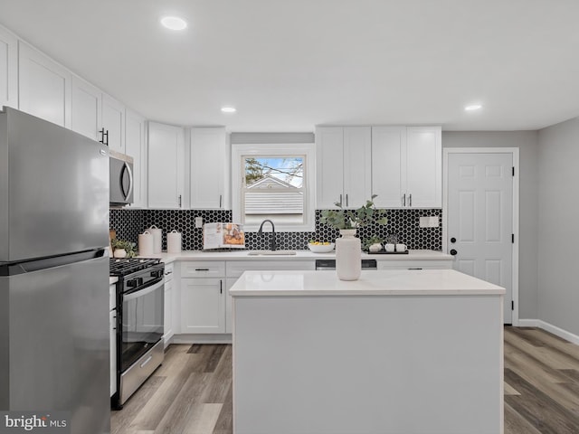 kitchen featuring sink, white cabinetry, appliances with stainless steel finishes, a kitchen island, and light hardwood / wood-style floors