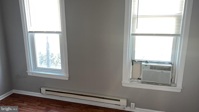 unfurnished room with dark hardwood / wood-style flooring, cooling unit, a wealth of natural light, and baseboard heating