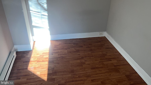 unfurnished room featuring dark hardwood / wood-style flooring and a baseboard radiator