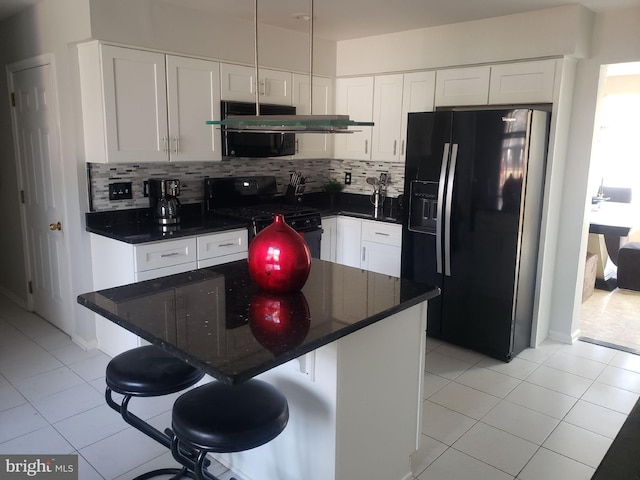 kitchen with black fridge, white cabinetry, a breakfast bar, and gas stove