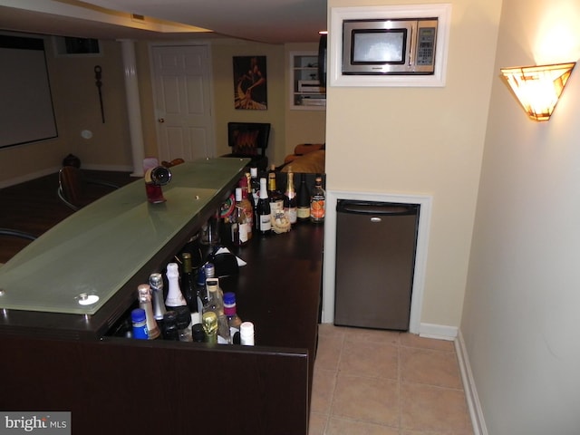 bar featuring appliances with stainless steel finishes and light tile patterned floors