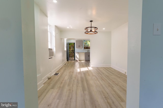 corridor featuring a notable chandelier and light wood-type flooring