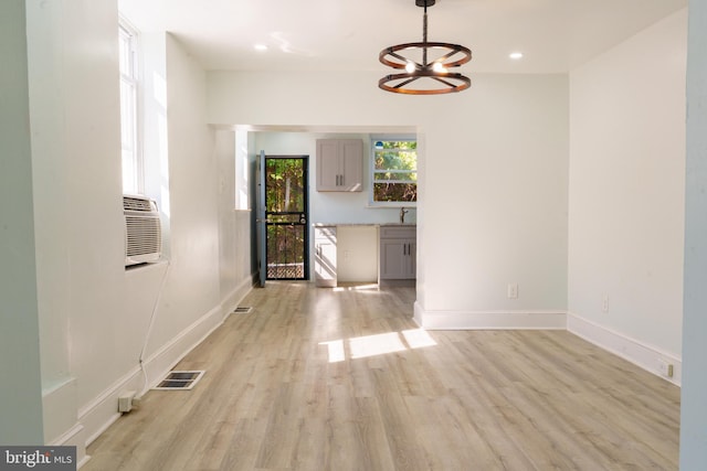 unfurnished dining area with sink, a notable chandelier, and light hardwood / wood-style floors