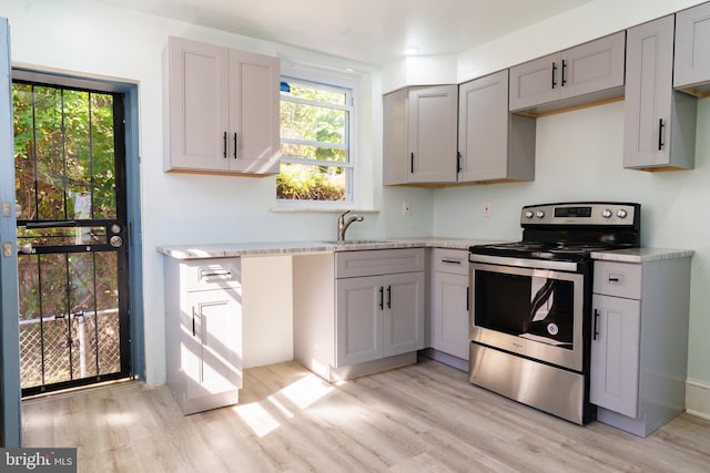 kitchen with sink, light hardwood / wood-style flooring, gray cabinetry, light stone countertops, and stainless steel electric range oven