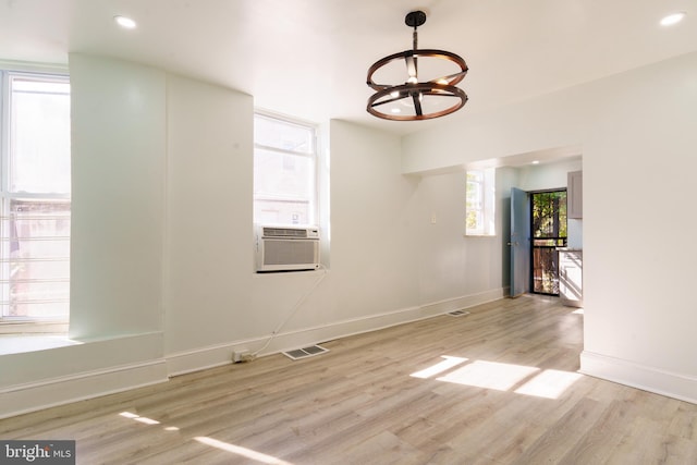 spare room featuring a chandelier, light wood-type flooring, and cooling unit