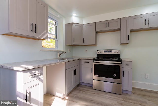 kitchen with sink, stainless steel range with electric stovetop, gray cabinetry, light hardwood / wood-style floors, and light stone countertops